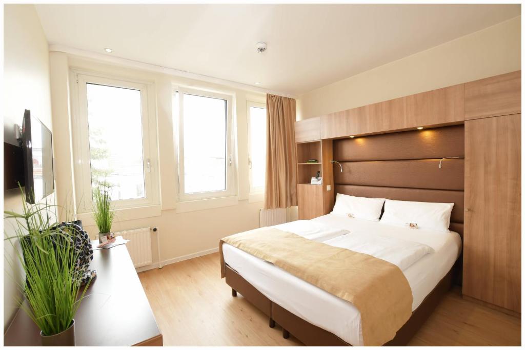 1 dormitorio con 1 cama grande y 2 ventanas en Motel Plus Berlin, en Berlín