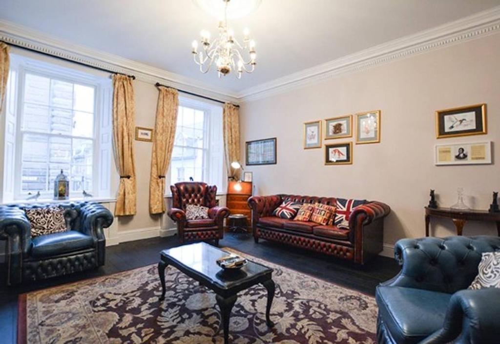 a living room with leather furniture and a chandelier at Reivers Apartment in Berwick-Upon-Tweed