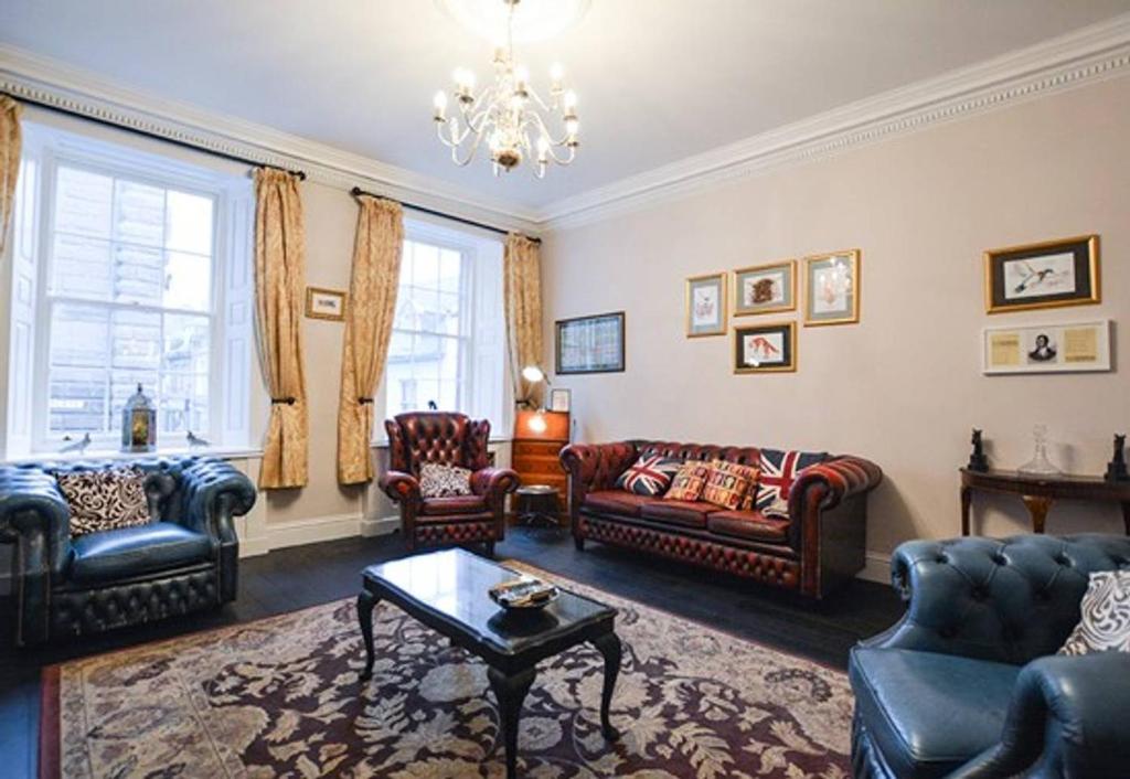 a living room with leather furniture and a chandelier at Reivers Apartment in Berwick-Upon-Tweed