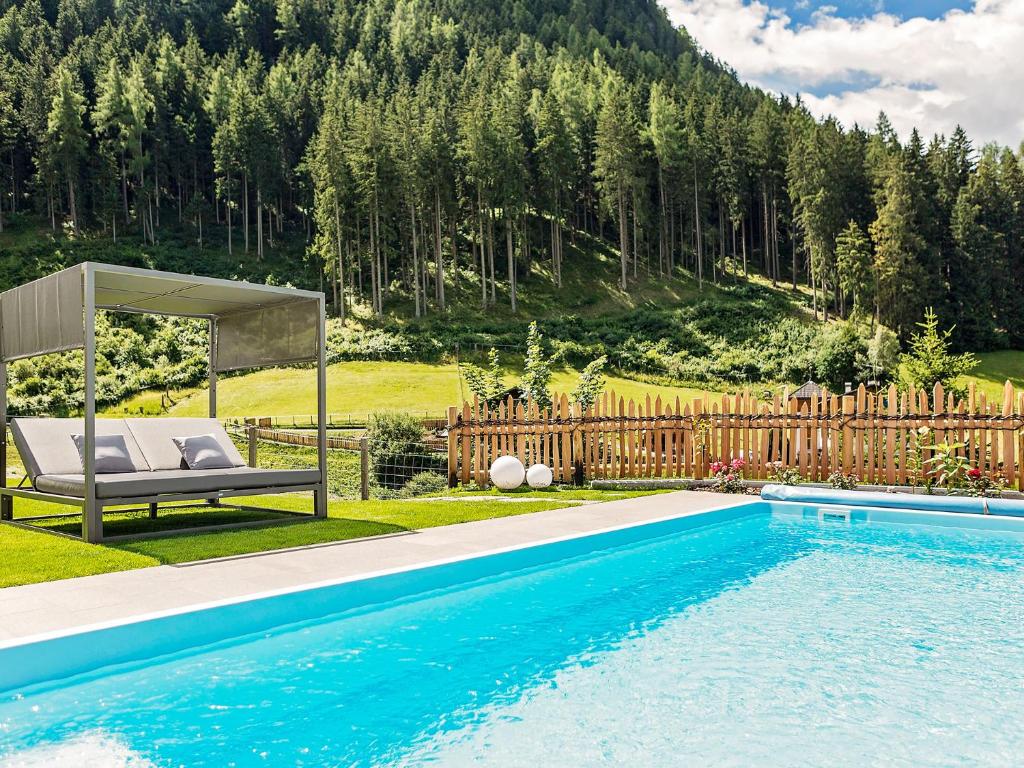 a swimming pool with a bench next to a fence at Residence Telemark in Santa Cristina in Val Gardena
