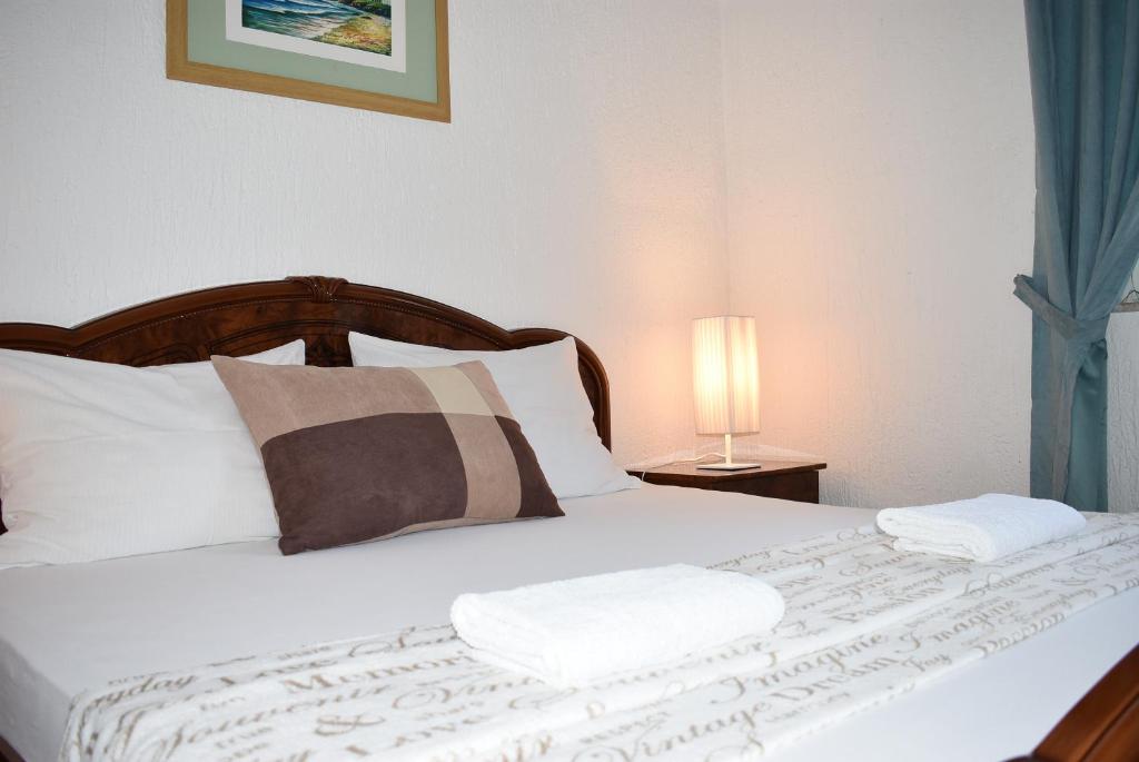 1 dormitorio con 1 cama con sábanas y almohadas blancas en Apartments Zara, en Zadar