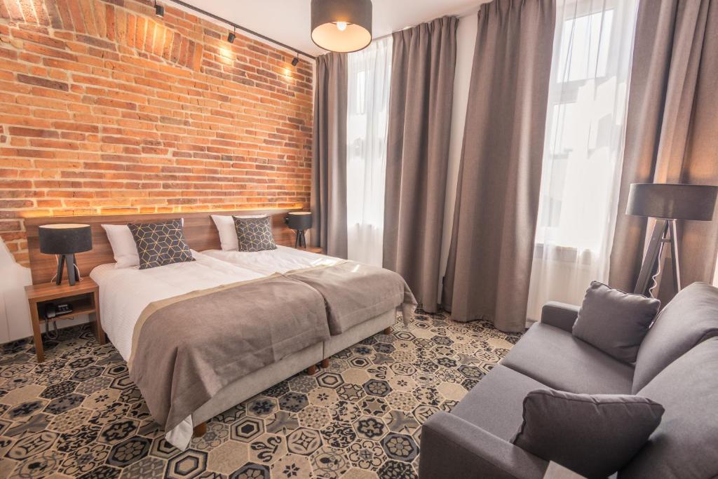 um quarto com uma cama e uma parede de tijolos em Hotel Lavender em Cracóvia
