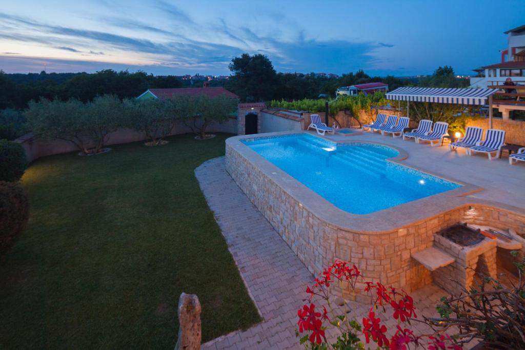a backyard with a swimming pool and a lawn with chairs at Villa Nicole in Banjole