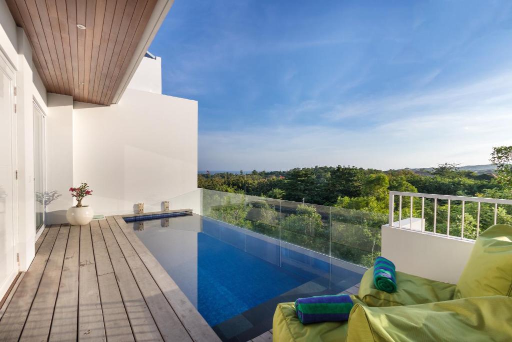 a house with a swimming pool and a balcony at Villa Melati R3 Ungasan in Uluwatu