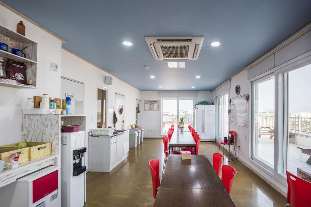 a kitchen with a wooden table and red chairs at Big O Show Guesthouse in Yeosu