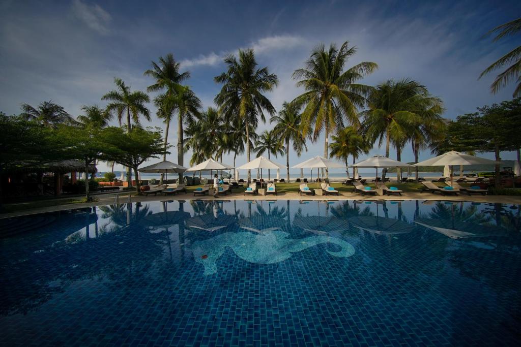 ein großer Pool mit Palmen und Sonnenschirmen in der Unterkunft Casa del Mar Langkawi in Pantai Cenang