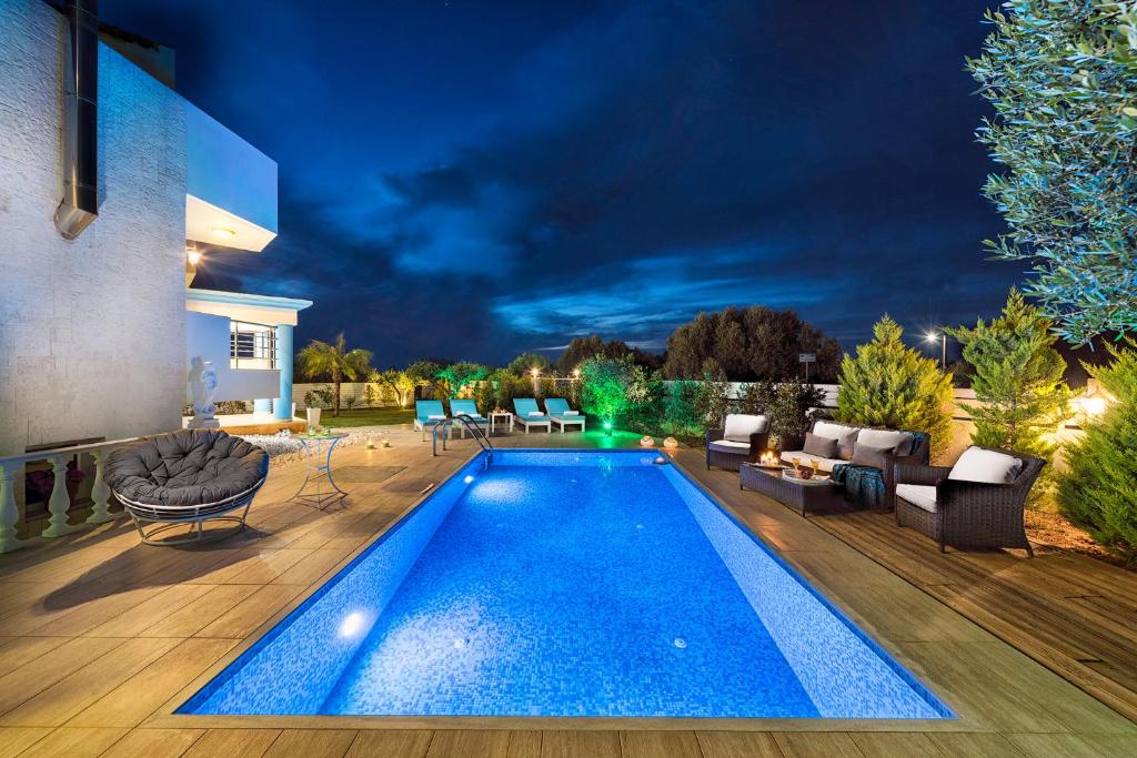 a swimming pool in the backyard of a house at night at Aphrodite Luxury Villa Hersonissos in Hersonissos