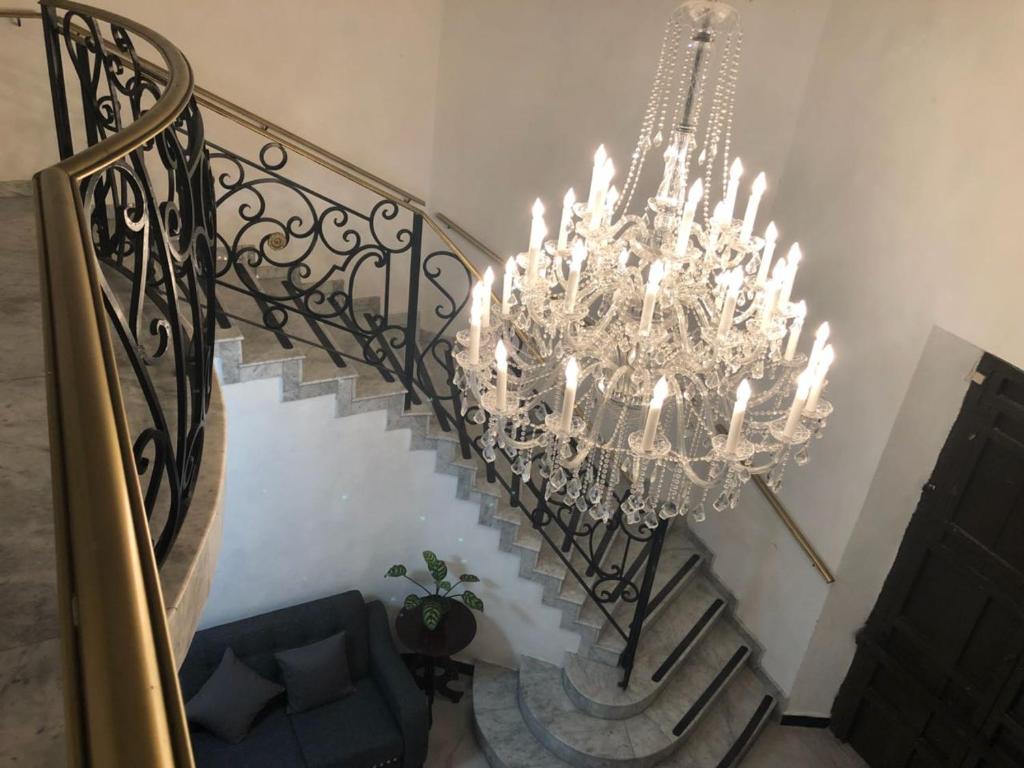 un escalier avec un lustre et un canapé dans l'établissement Izamal Plaza, à Izamal