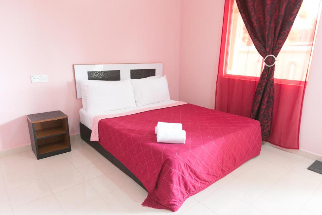 sypialnia z łóżkiem z czerwonym kocem i oknem w obiekcie Sri Melor Inn w mieście Pantai Cenang
