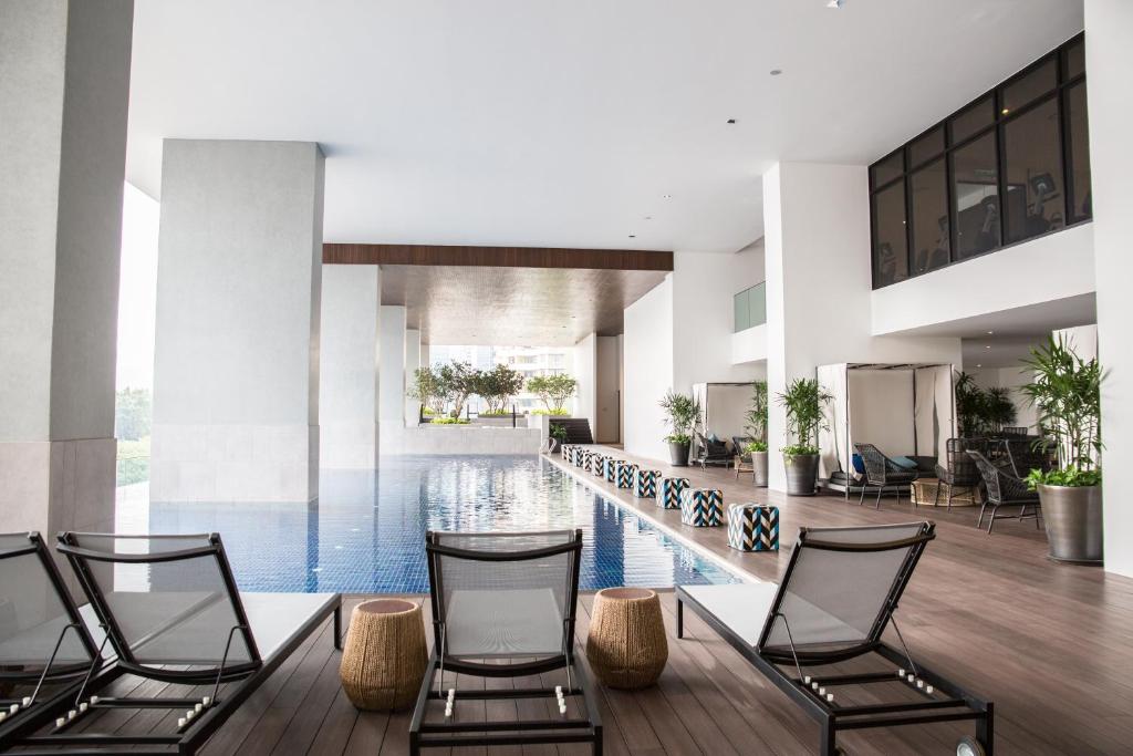 a lobby with a swimming pool with chairs and a table at The Establishment KL Sentral Bangsar by Plush in Kuala Lumpur