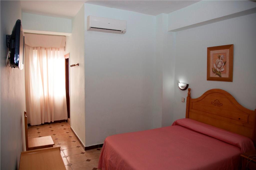 1 dormitorio con cama roja y ventana en Hostal París, en La Línea de la Concepción