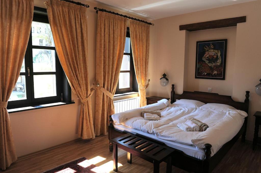 a bedroom with a large bed in front of windows at Kalin Hotel in Lazaropole