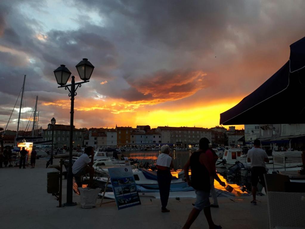 un groupe de personnes se promenant autour d'un port de plaisance au coucher du soleil dans l'établissement Apartment Sidro, à Cres