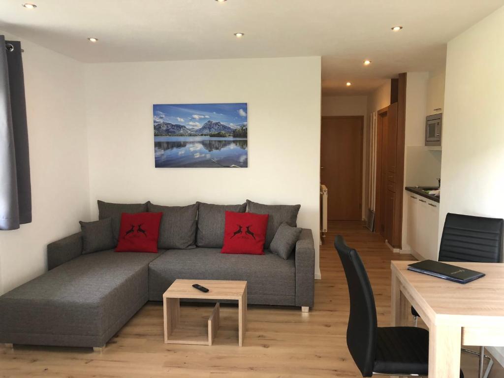 ein Wohnzimmer mit einem grauen Sofa und roten Kissen in der Unterkunft Ferienwohnung Hofer in Schwangau
