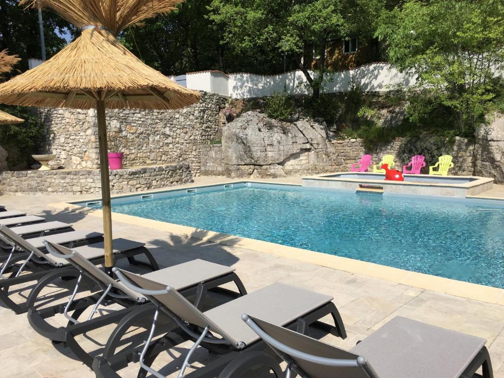 a group of chairs and an umbrella next to a swimming pool at Camping Chalets Les Chênes Verts in Vogüé