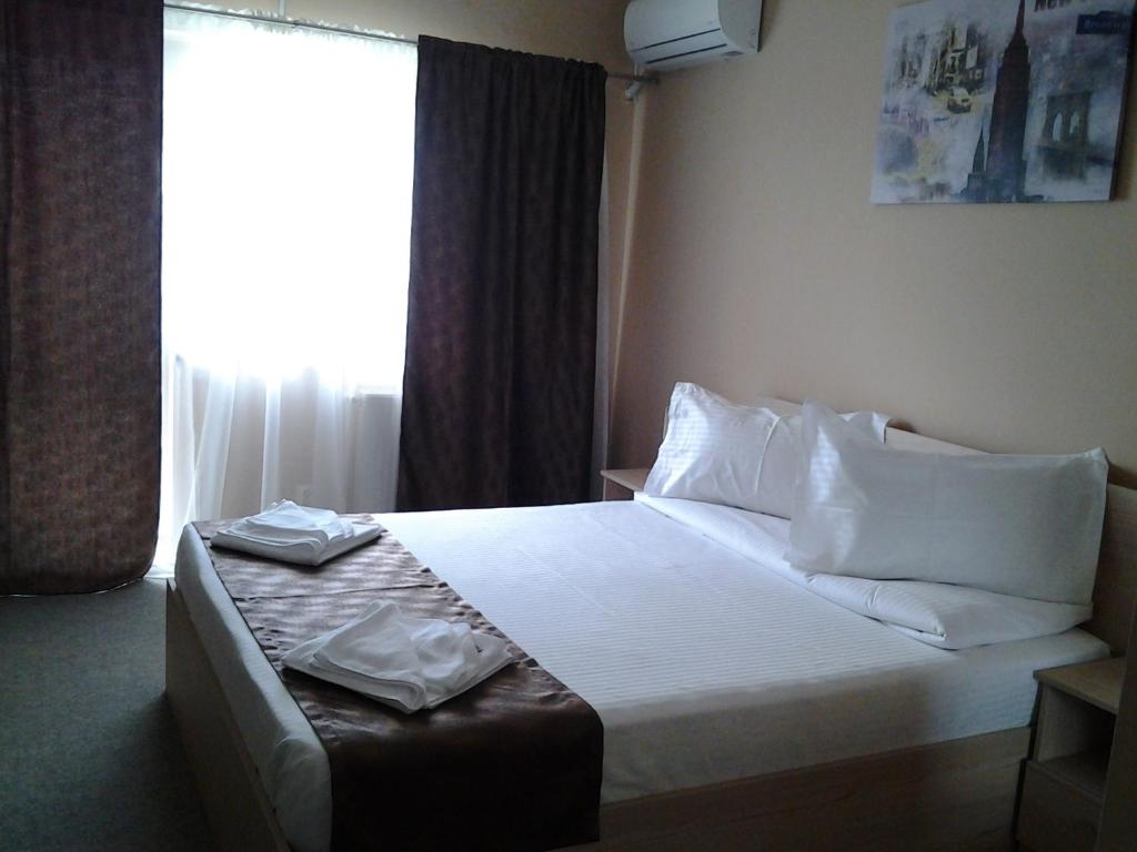 a hotel room with a bed with white sheets and pillows at Hostel Nova Route in Mamaia Nord