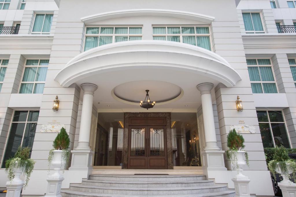 a large white building with a revolving door at The Rose Residence, Bangkok in Bangkok