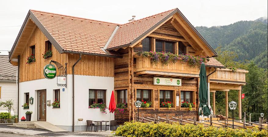 ein großes Holzgebäude mit Blumen davor in der Unterkunft Ferienwohnung Steirerbusserl in Kirchdorf