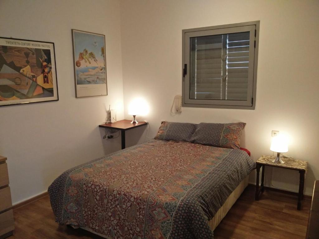 a bedroom with a bed and two lamps on tables at Herzelia Rooftop Special 2 Room Apartment in Herzliya