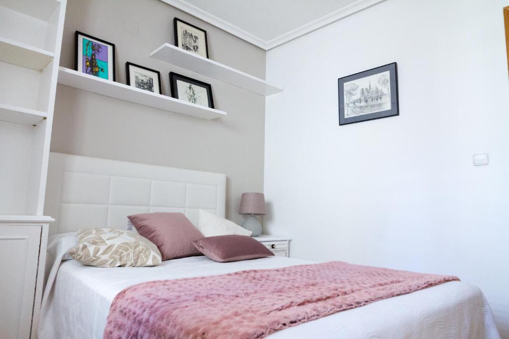 a white bedroom with a bed with a pink blanket at Apartamento Garcilaso de la Vega in Cuenca