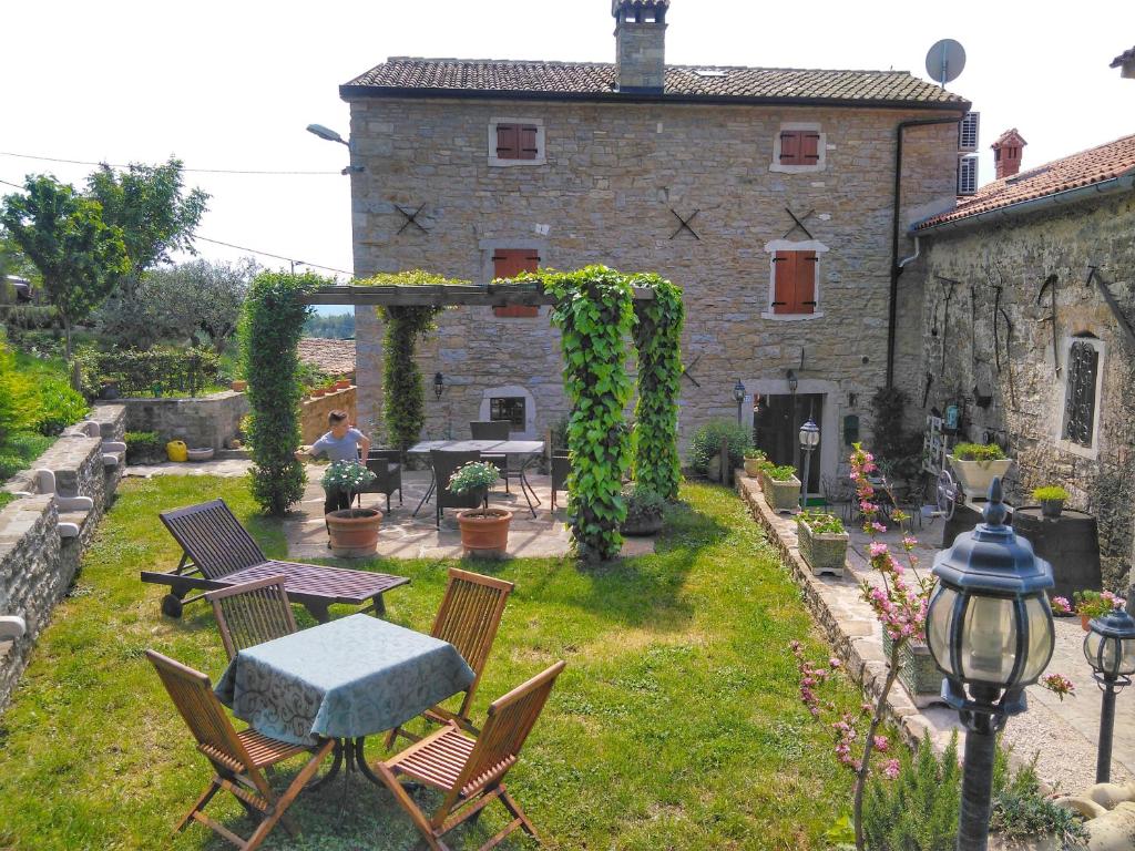 a garden with a table and chairs and a building at al Merlo Olivo, rural istrian house in Buje