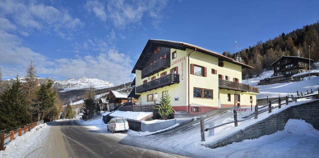 un bâtiment situé sur le côté d'une route dans la neige dans l'établissement Hotel Loredana, à Livigno