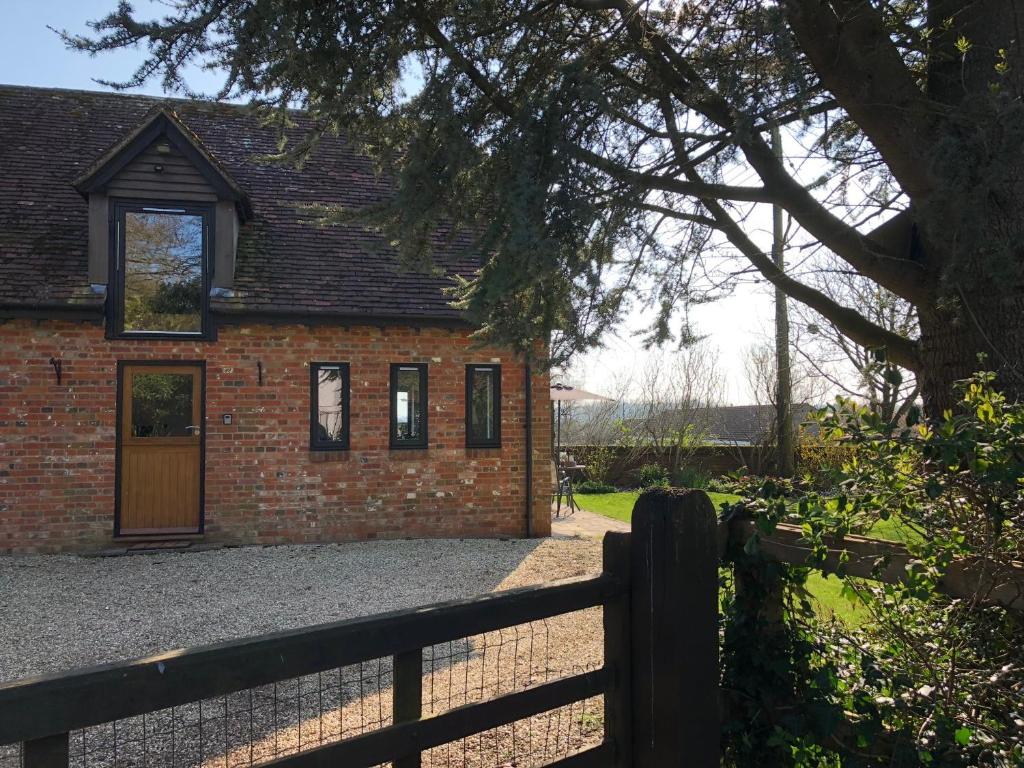 a brick house with a fence in front of it at The Stable Barn *On the edge of the New Forest* in Downton