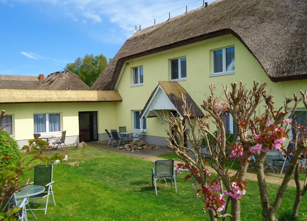 una casa amarilla con sillas y un patio de césped en Uns Wiek-Hus, en Middelhagen