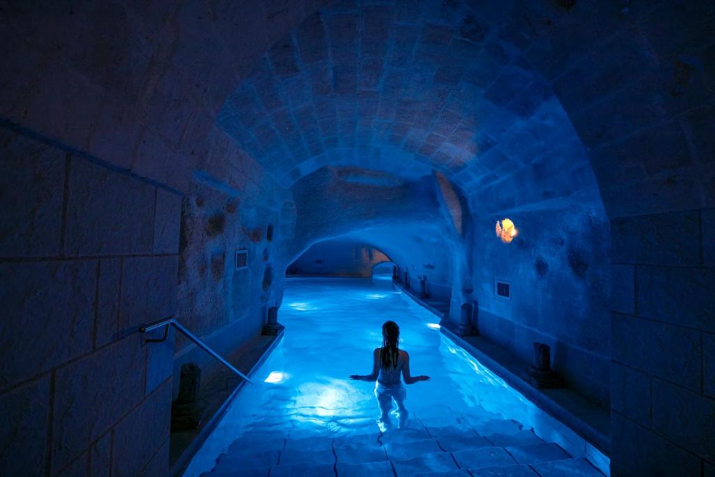 a person standing in a blue tunnel at Locanda Di San Martino Hotel & Thermae Romanae in Matera