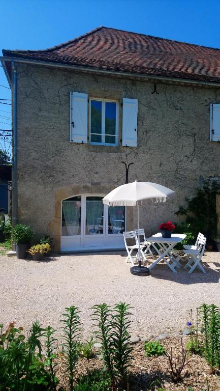 une maison avec une table, deux chaises et un parasol dans l'établissement Appartement Duplex, à Bretenoux