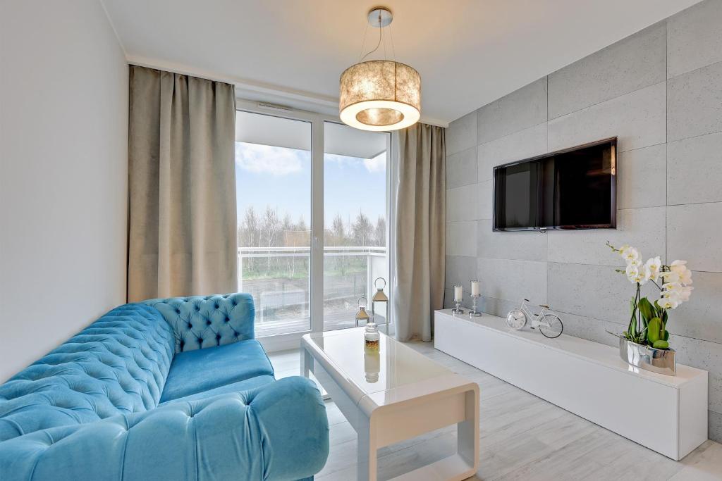 ein Wohnzimmer mit einem blauen Sofa und einem TV in der Unterkunft Apartament Mistral Gdynia in Gdynia