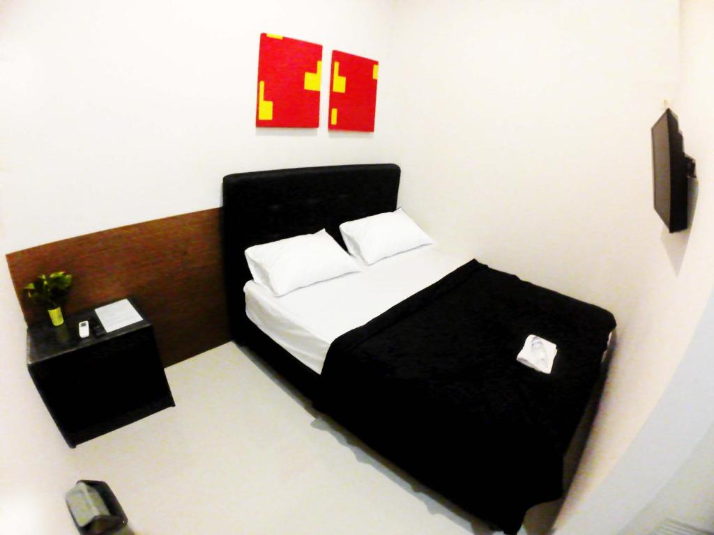 a bedroom with a black bed with two white pillows at login homestay in Madiun