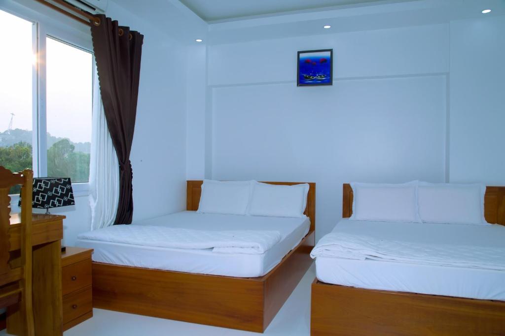 2 camas en una habitación con ventana en Hotel Đăng Khôi Núi Sam en Chau Doc