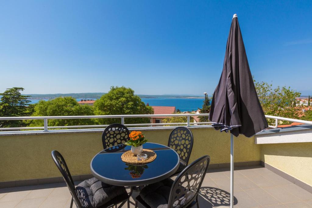 einen Tisch und Stühle auf einem Balkon mit Sonnenschirm in der Unterkunft Apartments Claudia in Crikvenica