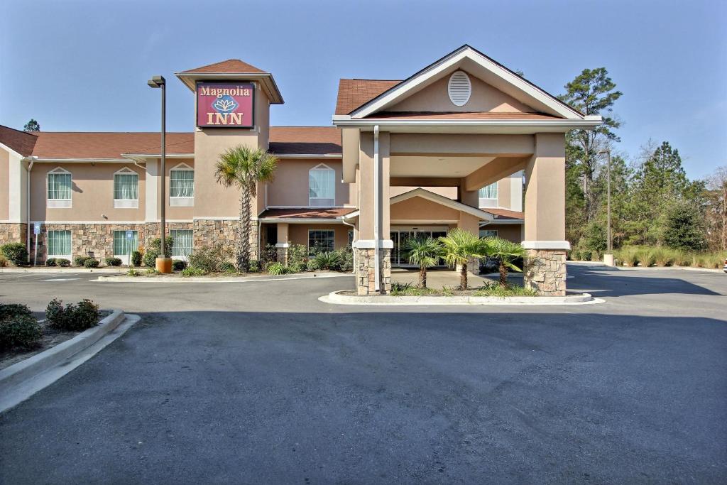 un hotel con un estacionamiento delante de él en Magnolia Inn and Suites Pooler, en Savannah