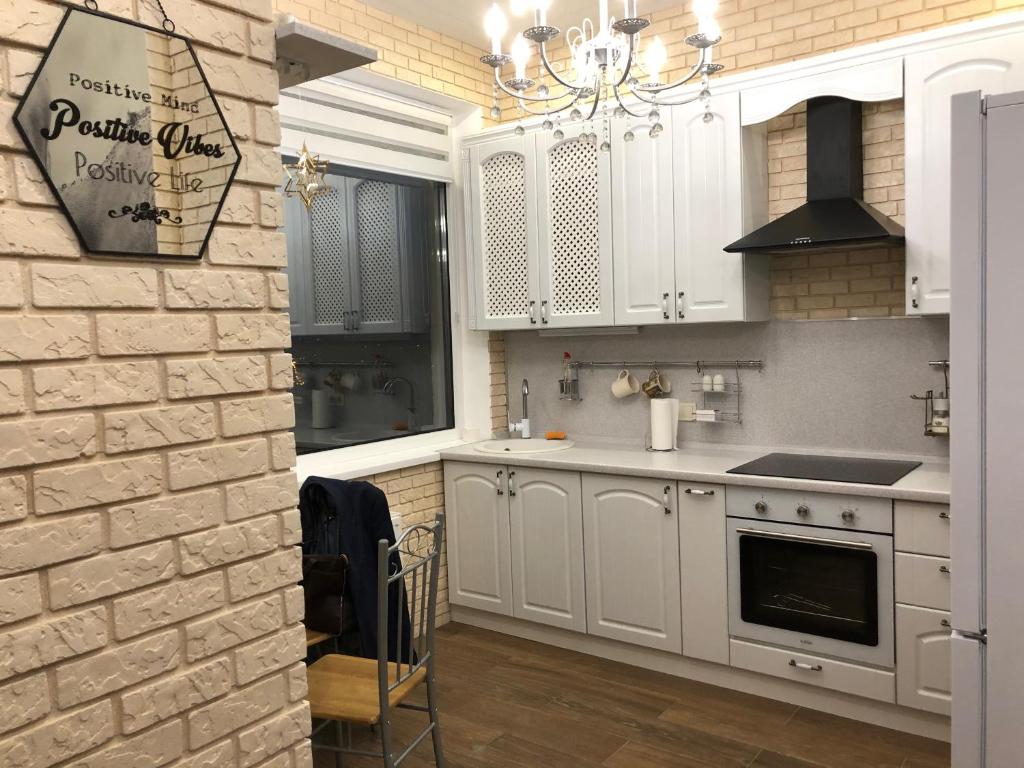 オデッサにあるZhemchuzhnie apartments on Marselskayaの白いキャビネットとレンガの壁が備わるキッチン