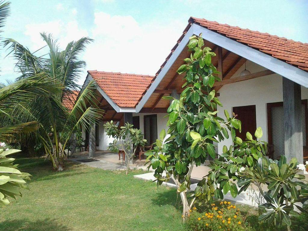 Una casa blanca con un árbol delante. en Villa Nilaveli Cabana, en Nilaveli