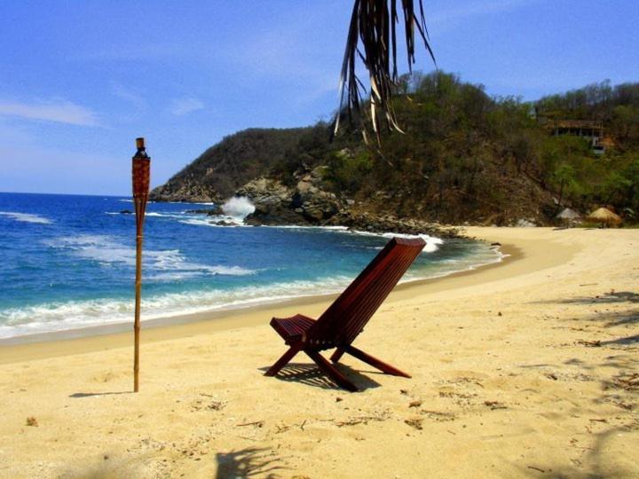 una silla sentada en una playa junto a un poste en Hotel Bahía de la Luna en Arroyo Cruz