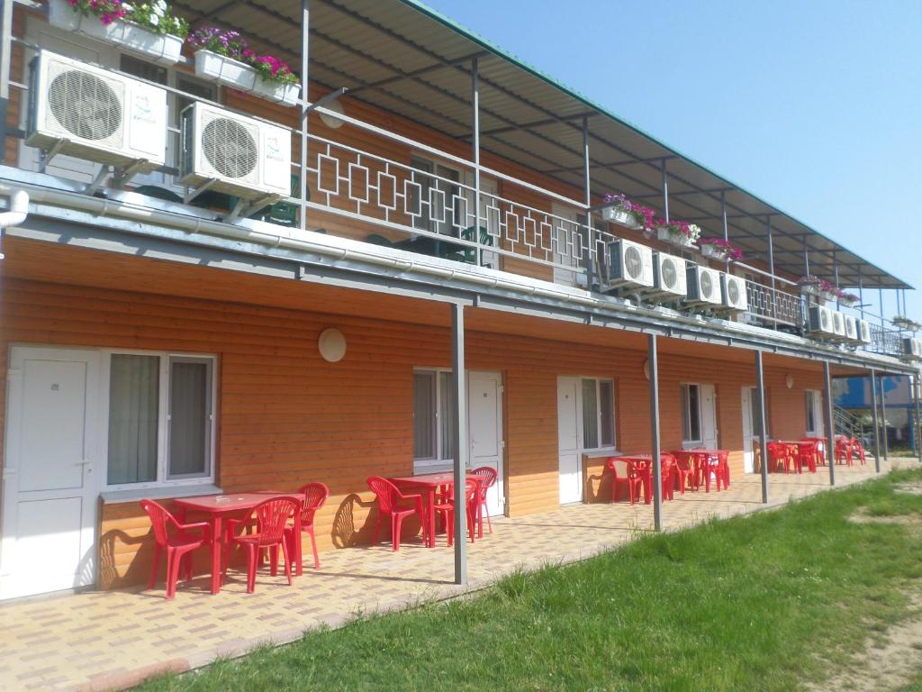 Zolotoy Bereg Hotel في زاتوكا: مجموعة من الطاولات والكراسي الحمراء على جانب المبنى