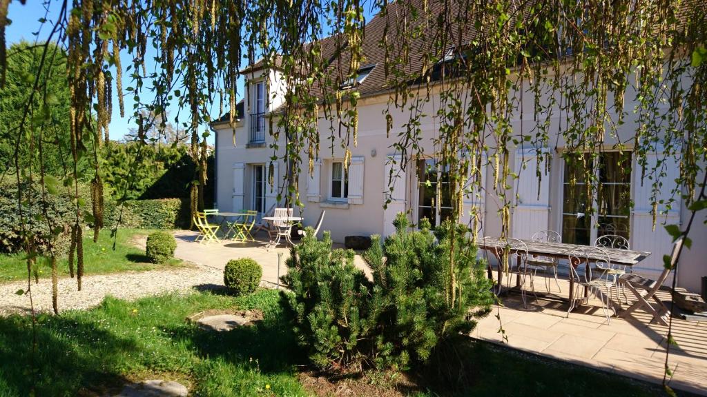 una casa blanca con una mesa de picnic delante de ella en Chambre d'Elisabeth à la Ferme en Montépilloy