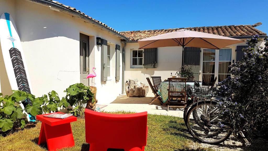 サン・クレマン・デ・バレーヌにあるVillas Ré Locations Vacancesの傘とテーブルと椅子が備わる家