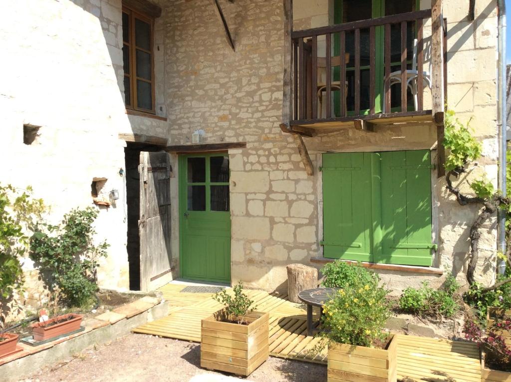 a house with green doors and a table on a porch at Gîte Pays de la Loire in Vézières