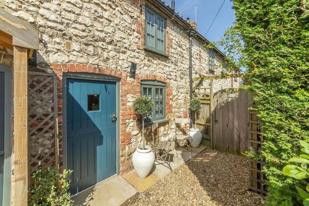 a brick house with a blue door and a fence at No33 THORNHAM BOUTIQUE COTTAGE 2 in Thornham