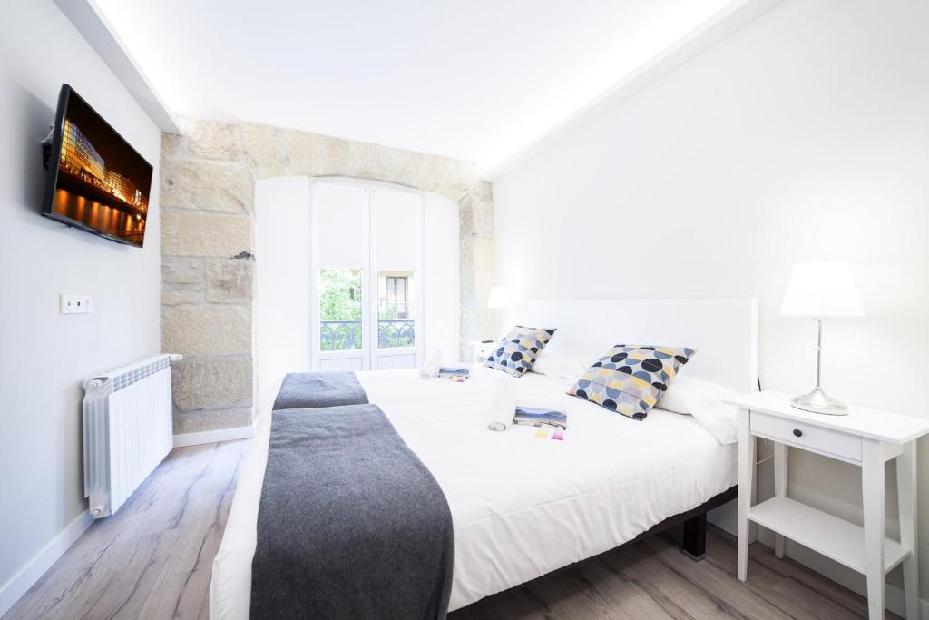 a white bedroom with a bed and a window at Central Park II - SSHousing in San Sebastián