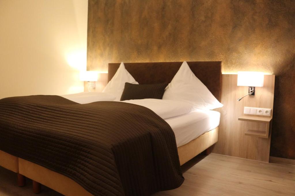 a bedroom with a bed with white sheets and two lamps at Hotel Baldus in Delmenhorst
