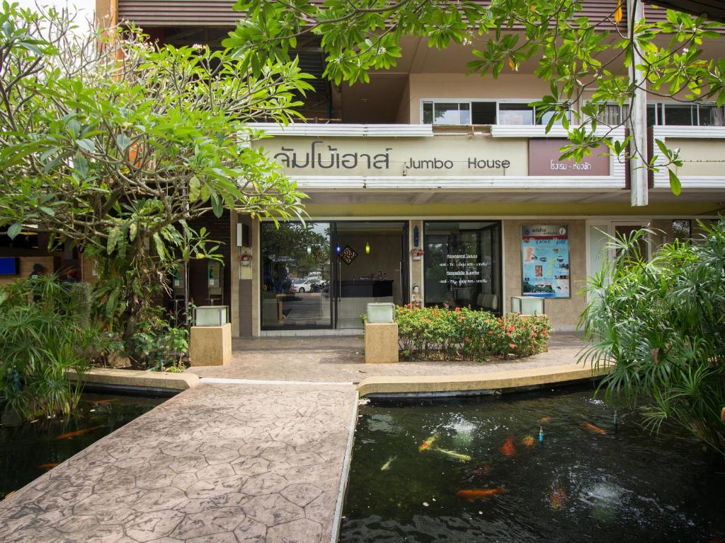 a building with a koi pond in front of it at Jumbo House in Tha Sae