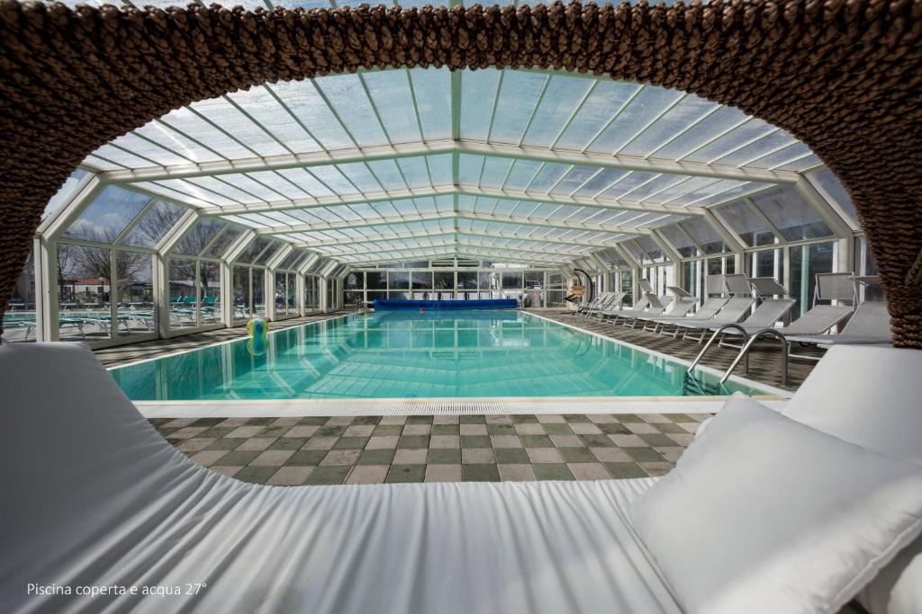 une grande piscine avec des chaises et un plafond en verre dans l'établissement Camping Da Giovanni, à Peschiera del Garda