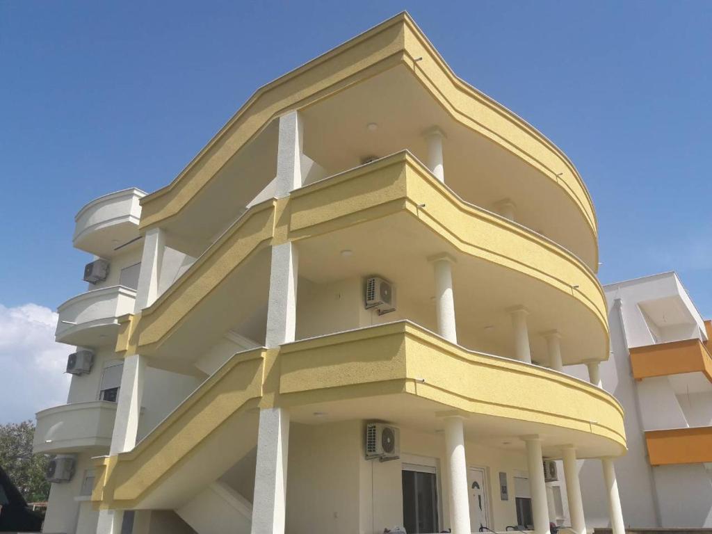 a yellow and white building with a blue sky at Korac Apartments in Ulcinj