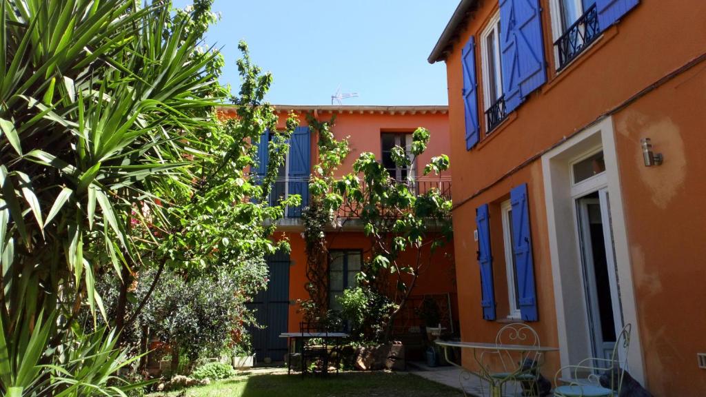 una casa naranja con ventanas y plantas azules en Votre adresse de charme centre historique de Béziers, en Béziers