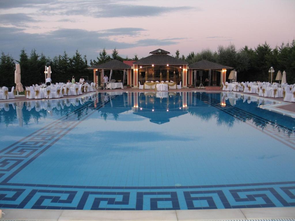 a wedding venue with a large pool with white chairs at Hotel Aiges Melathron in Veria